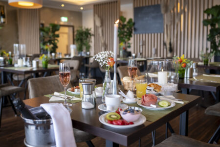 Festlich gedeckter Frühstückstisch mit frischen Brötchen, Obst, Wurst, Müsli und Getränken im Restaurant des Hotel Rheingarten