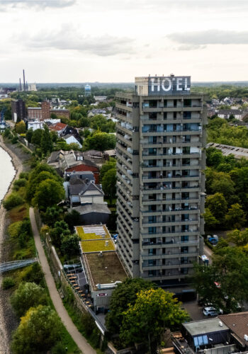Drohnenaufnahme des Hotel Rheingarten direkt am Rhein mit vorbeifahrendem Schiff und Blick über die Stadt