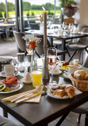 Festlich gedeckter Frühstückstisch im Hotel Rheingarten mit frischen Brötchen, Obst, Getränken und Blick auf die Terrasse