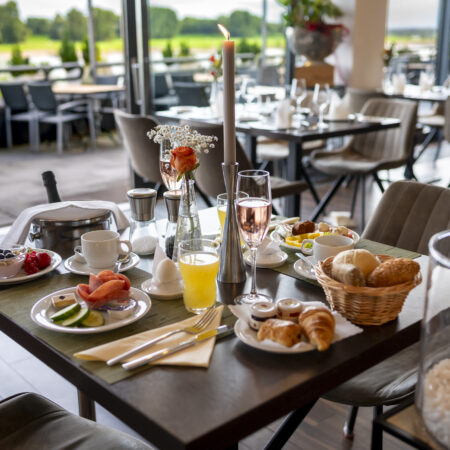 Festlich gedeckter Frühstückstisch im Hotel Rheingarten mit frischen Brötchen, Obst, Getränken und Blick auf die Terrasse