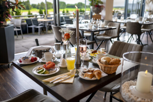 Festlich gedeckter Frühstückstisch im Hotel Rheingarten mit frischen Brötchen, Obst, Getränken und Blick auf die Terrasse