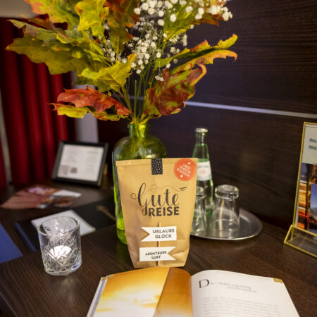 Dekorierter Schreibtisch im Hotel Rheingarten mit Vase, Kerze, Getränken und einer Guten-Reise-Tüte