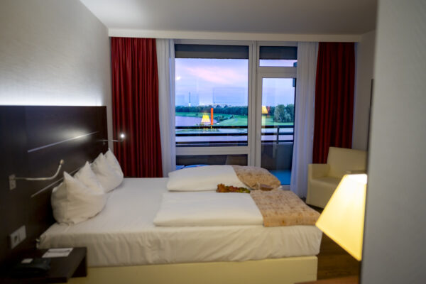 Gemütliches Doppelzimmer im Hotel Rheingarten mit Balkon und Blick auf den Rhein bei Abendstimmung.