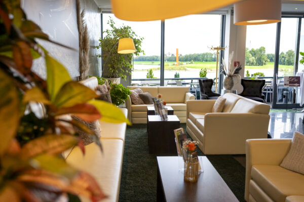 Gemütlicher Lounge-Bereich im Hotel Rheingarten mit modernen Sitzmöbeln, stilvoller Dekoration und Blick auf den Rhein durch große Panoramafenster.