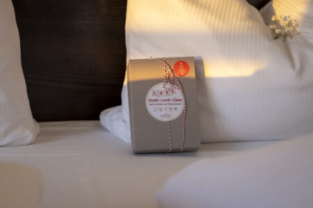 Geschenkbox Stadt-Land-Liebe im Hotel Rheingarten, liebevoll dekoriert als Aufmerksamkeit auf dem Hotelbett.