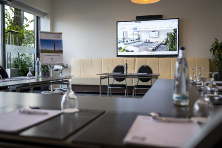 Moderner Tagungsraum im Hotel Rheingarten mit großer Leinwand und Konferenzbestuhlung, ausgestattet für Präsentationen und Meetings.
