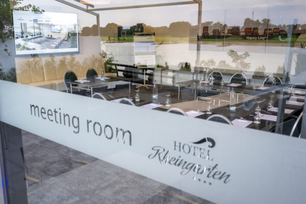 Blick durch die Glasfront in den Tagungsraum des Hotel Rheingarten mit moderner Ausstattung und Rheinblick.
