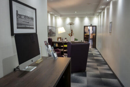 Gemütliche Lounge im Hotel Rheingarten in Duisburg mit Sesseln, Computer-Arbeitsplatz, Lesematerialien und stilvoller Dekoration.