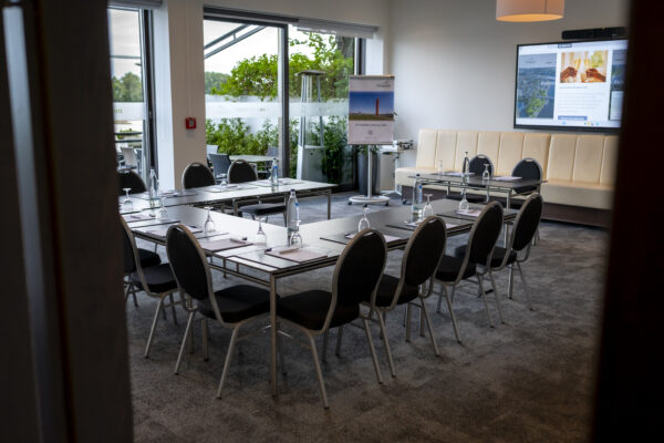 Moderner Tagungsraum im Hotel Rheingarten in Duisburg mit Konferenztischen, Bestuhlung, großer Präsentationsfläche und Blick auf die Terrasse.