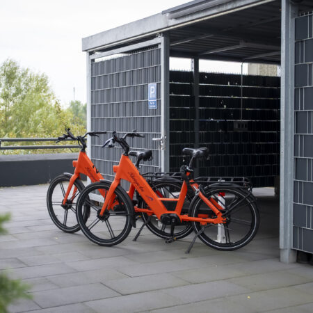 Überdachter Stellplatz mit leuchtend orangefarbenen Leihfahrrädern des Hotel Rheingarten in Duisburg-Homberg.