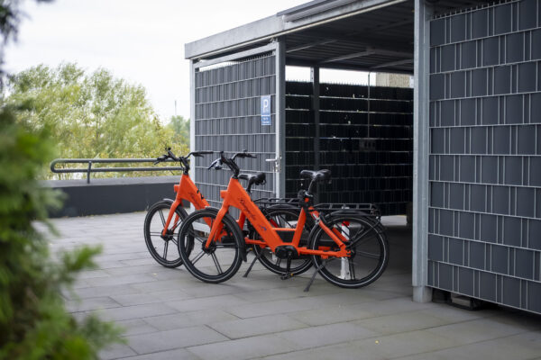 Überdachter Stellplatz mit leuchtend orangefarbenen Leihfahrrädern des Hotel Rheingarten in Duisburg-Homberg.