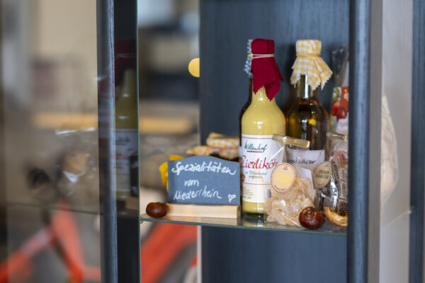 Glasvitrine im Hotel Rheingarten mit regionalen Hofladen-Produkten wie Likör, Honig, Marmelade und eingelegtem Gemüse vom Niederrhein.