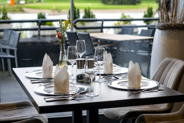 Stilvoll gedeckter Tisch im Restaurant des Hotel Rheingarten mit Blick auf den Rhein, eleganten Gläsern, Servietten und moderner Tischdekoration.