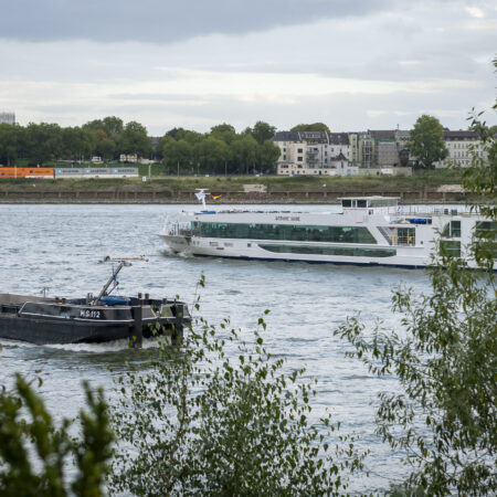 Blick vom Hotel Rheingarten auf den Rhein mit vorbeifahrenden Schiffen und der Stadt Duisburg im Hintergrund.