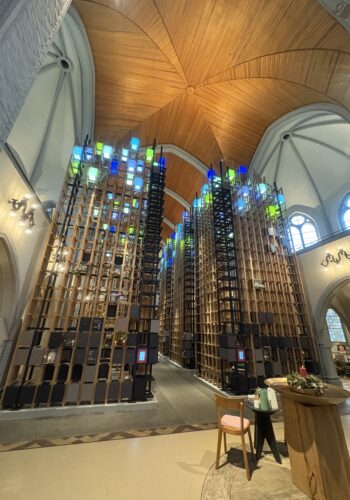 Innenraum des Kolumbarium Duisburg mit hohen Urnenwänden und farbig beleuchteten Elementen unter dem Kirchendach.