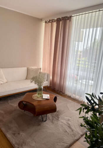 Gemütlicher Wohnbereich im Hotelzimmer mit Sofa, Couchtisch und Vorhängen