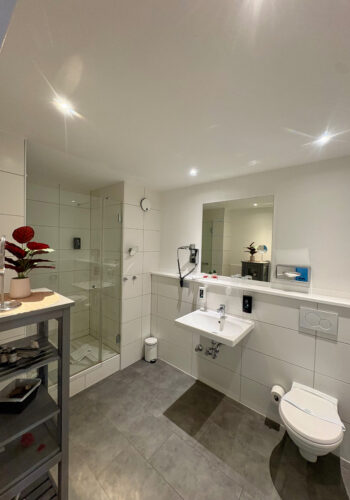 Modernes Badezimmer im Hotelzimmer mit Dusche, Waschbecken und Spiegel