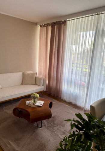 Wohnbereich im Hotelzimmer mit Sofa, Couchtisch und hellem Balkonfenster