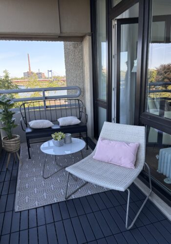 Balkon mit Liegestuhl, Lounge-Sitzbank und kleinem Tisch vor einem weiten Wasserpanorama