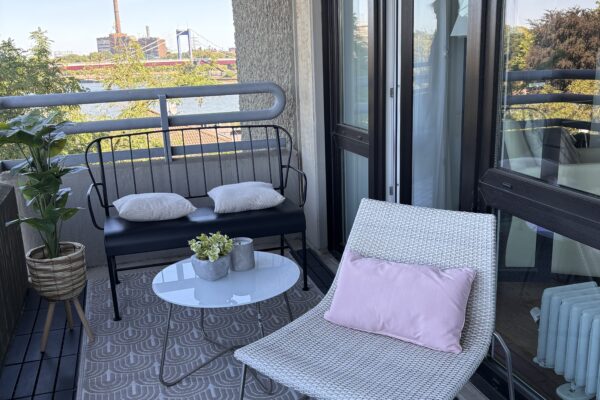 Balkon mit Liegestuhl, Lounge-Sitzbank und kleinem Tisch vor einem weiten Wasserpanorama